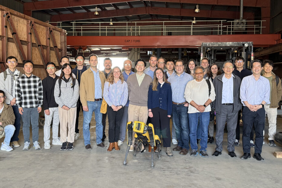 A group of 25 people stand in a testing laboratory.